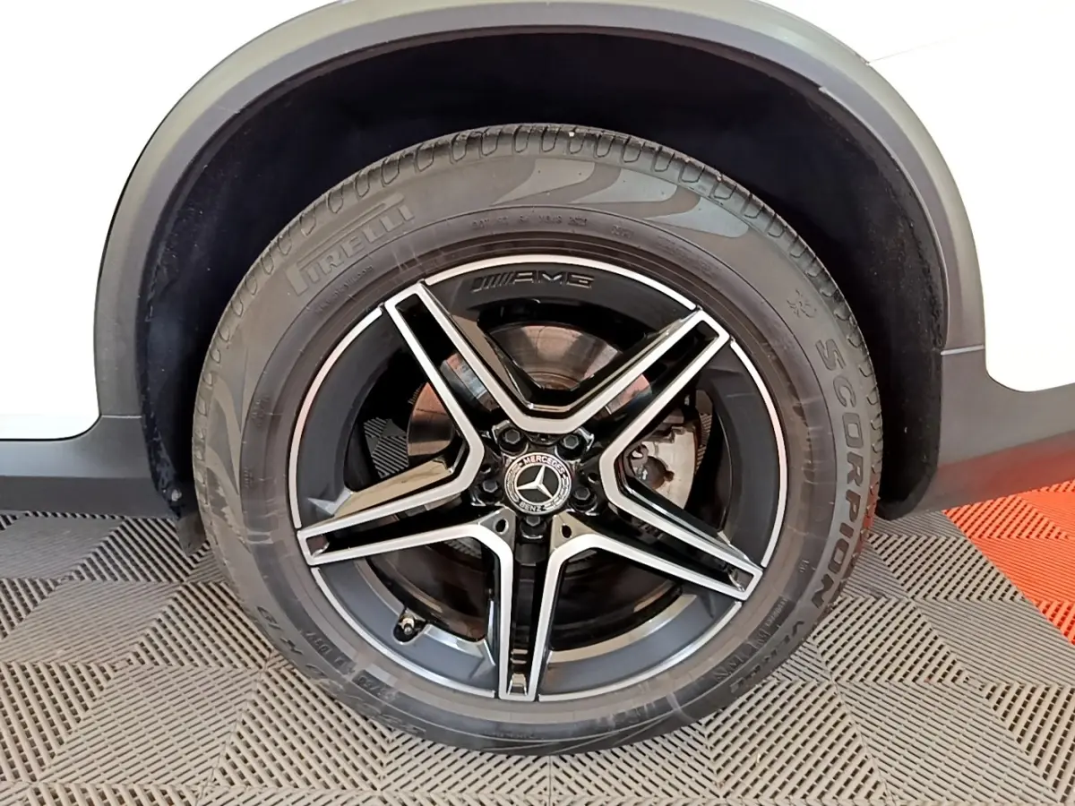 Gros plan sur la roue avant droite noire AMG avec jante étoile sur Mercedes GLC Coupé blanc.