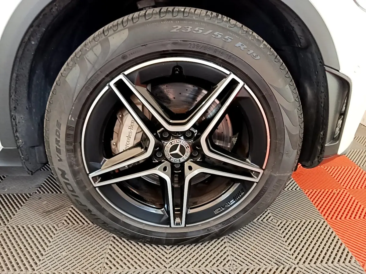 Gros plan sur la roue avant gauche du Mercedes GLC 300 e AMG Line blanc, jante alliage noir à cinq branches.