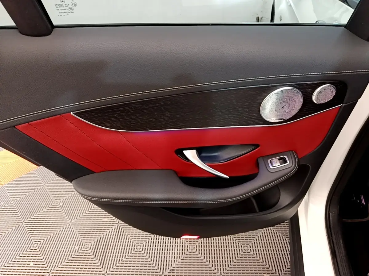 Gros plan sur la porte côté gauche d’un Mercedes GLC 300 e AMG Line blanc, avec intérieur cuir rouge et noir.