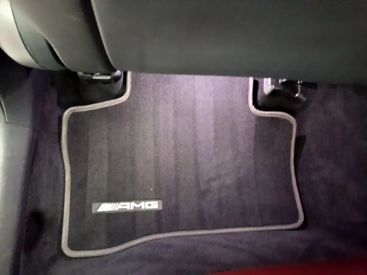 Tapis de sol noir avec logo AMG visible à l'avant droit dans l'habitacle d'un Mercedes GLC Coupé blanc.