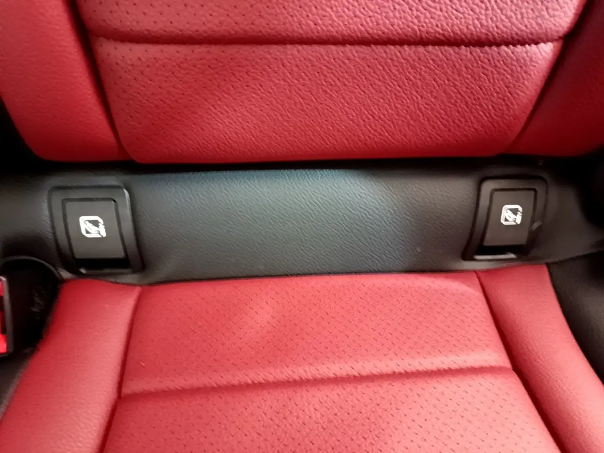 Gros plan sur la banquette arrière rouge avec fixation Isofix visible dans un Mercedes GLC Coupé blanc.