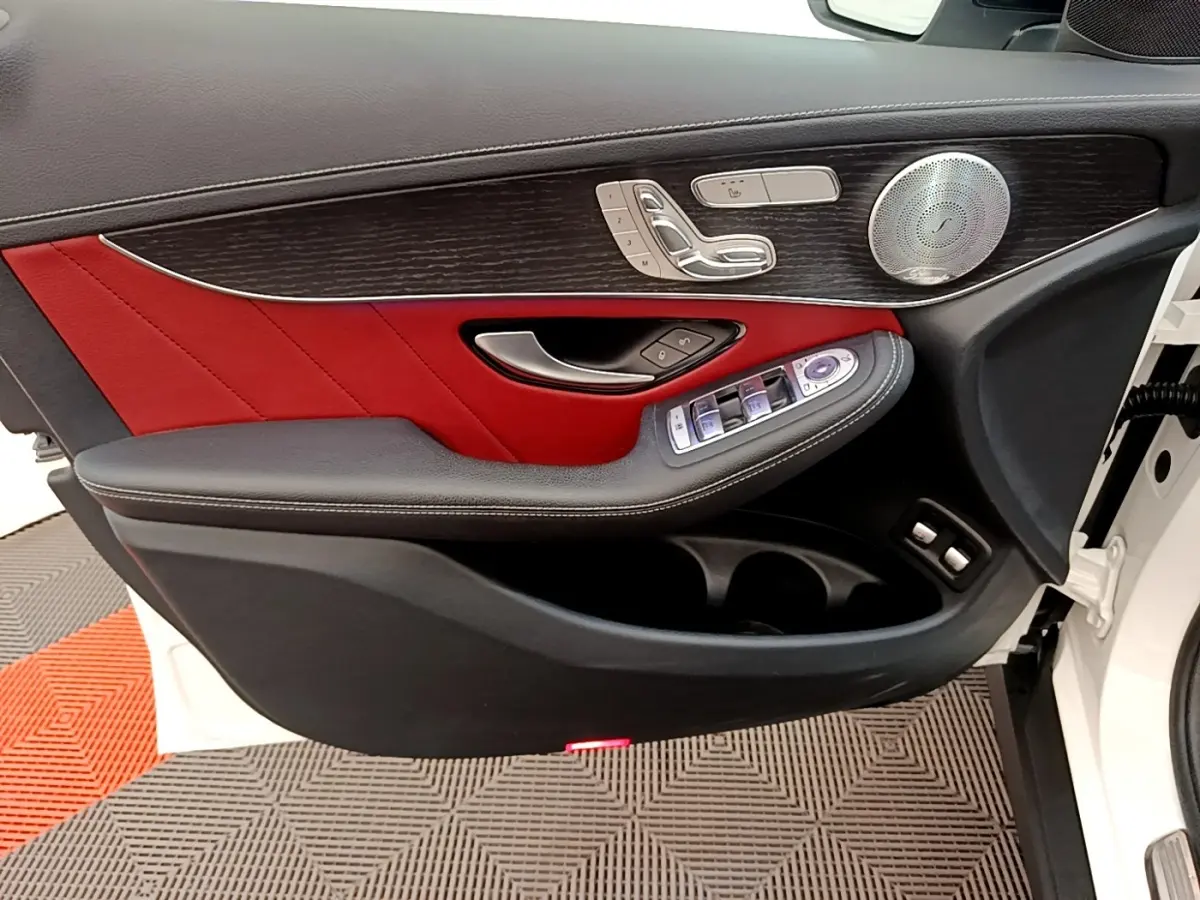 Vue intérieure côté gauche de la porte avant blanche du Mercedes GLC 300 e AMG Line avec garniture cuir rouge et bois.