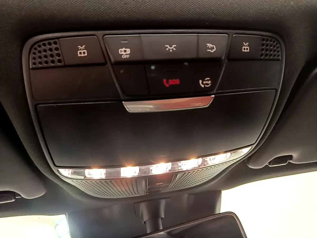 Vue en gros plan du plafonnier intérieur avec commandes d’éclairage et bouton SOS du Mercedes GLC 300 e AMG Line blanc.