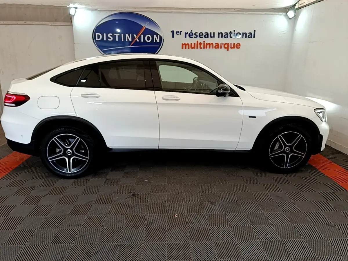Profil côté gauche d'un Mercedes GLC Coupé blanc 2020 AMG Line avec jantes noires et toit incliné.
