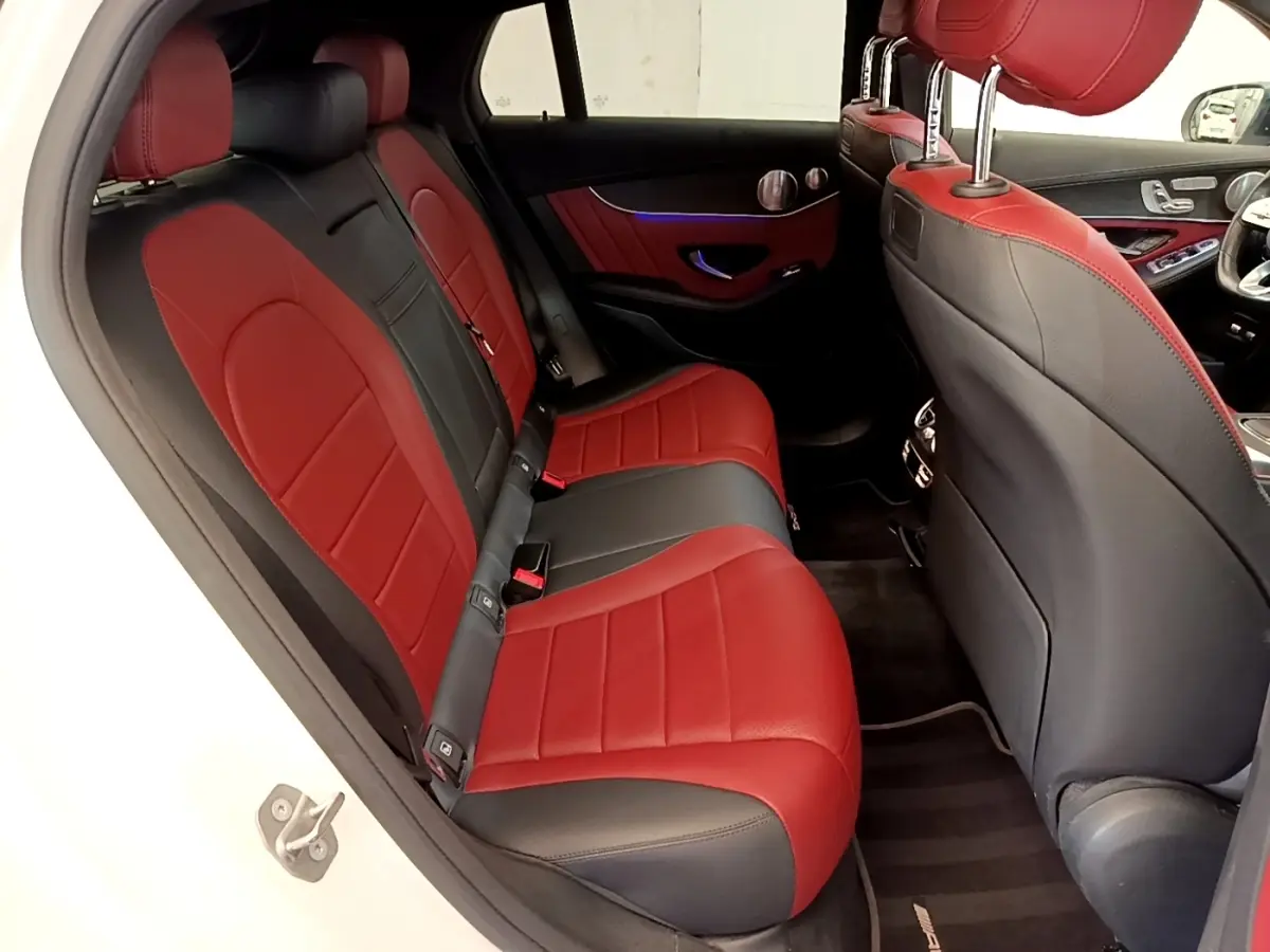 Vue intérieure arrière droite du Mercedes GLC 300 e AMG Line blanc, sièges cuir bicolores rouge et noir.