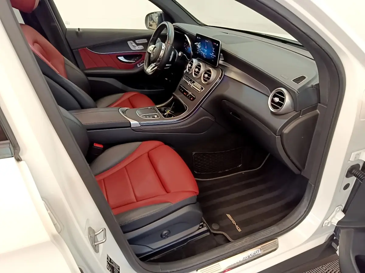 Vue intérieure côté conducteur du Mercedes GLC 300 e AMG Line blanc avec sièges cuir rouge et tableau de bord moderne.