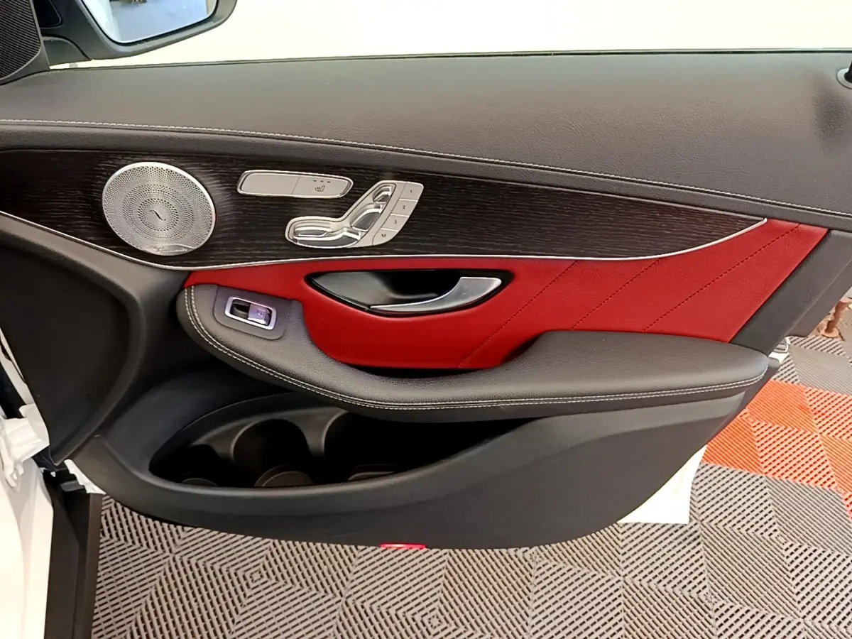 Gros plan sur la porte avant gauche du Mercedes GLC 300 e AMG Line blanc, avec garniture cuir rouge et commandes mémoire sièges.