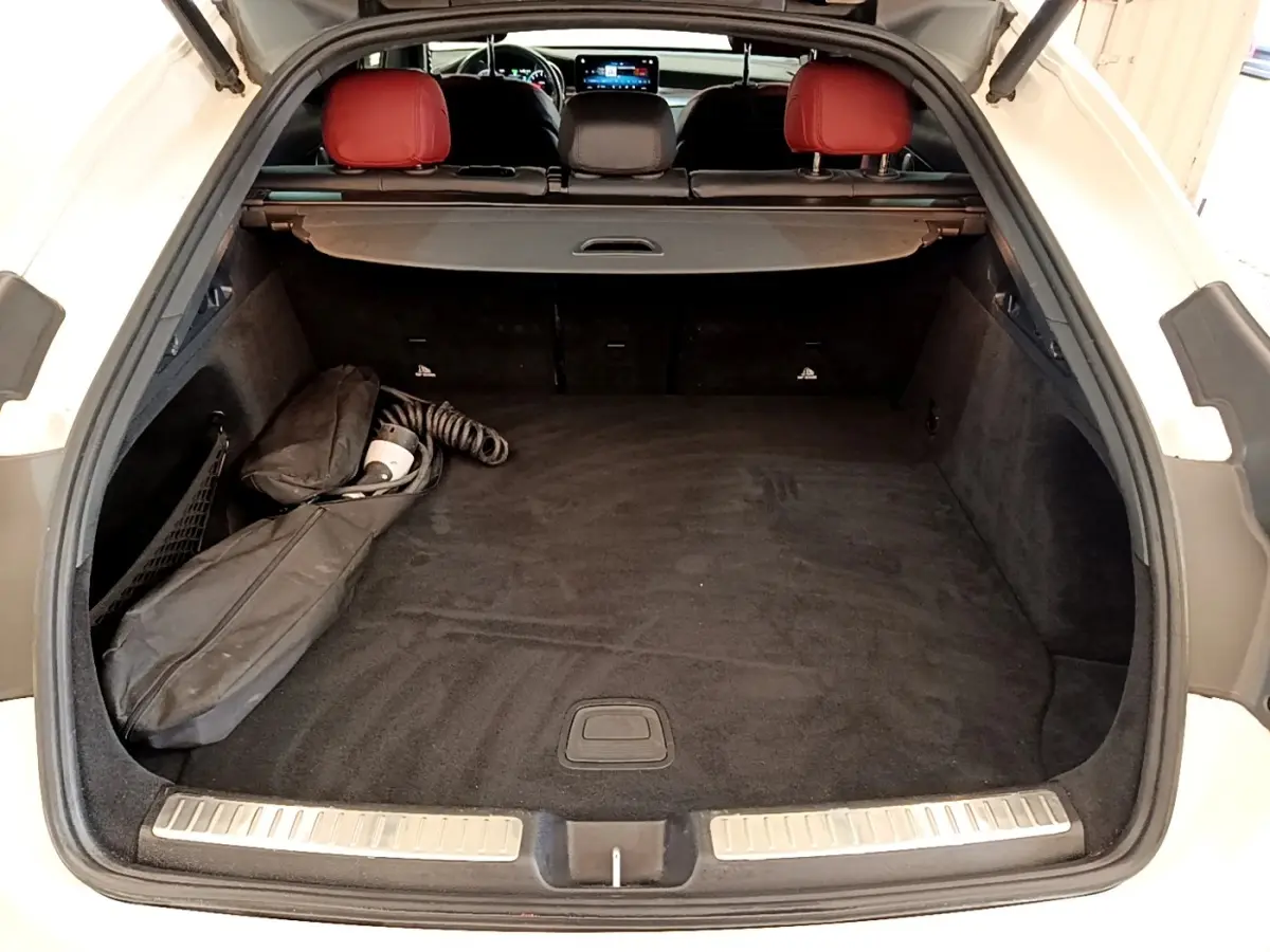 Vue arrière du coffre ouvert d'un Mercedes GLC Coupé blanc avec intérieur noir et appuis-tête rouges visibles.