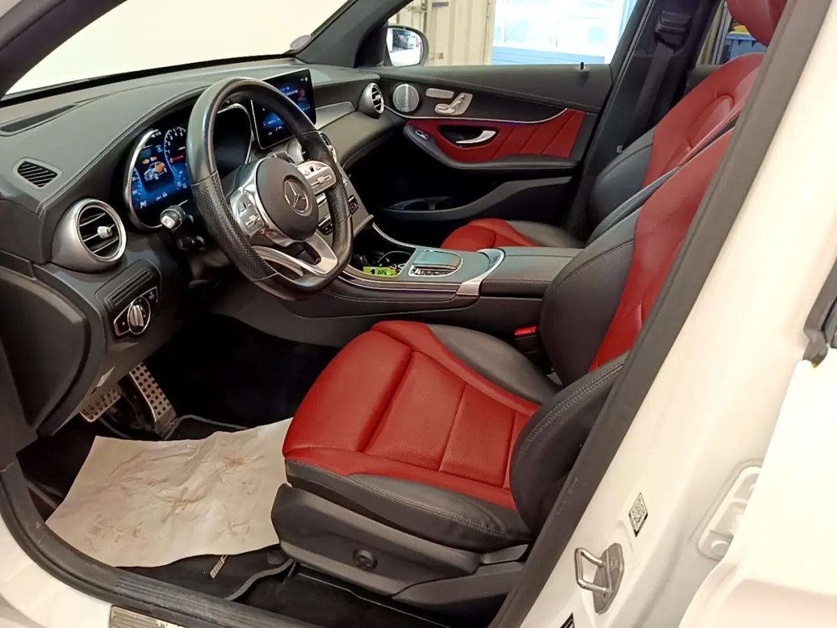 Vue intérieure côté conducteur du Mercedes GLC Coupé blanc de 2020, sièges cuir rouge et noir avec tableau de bord digital.