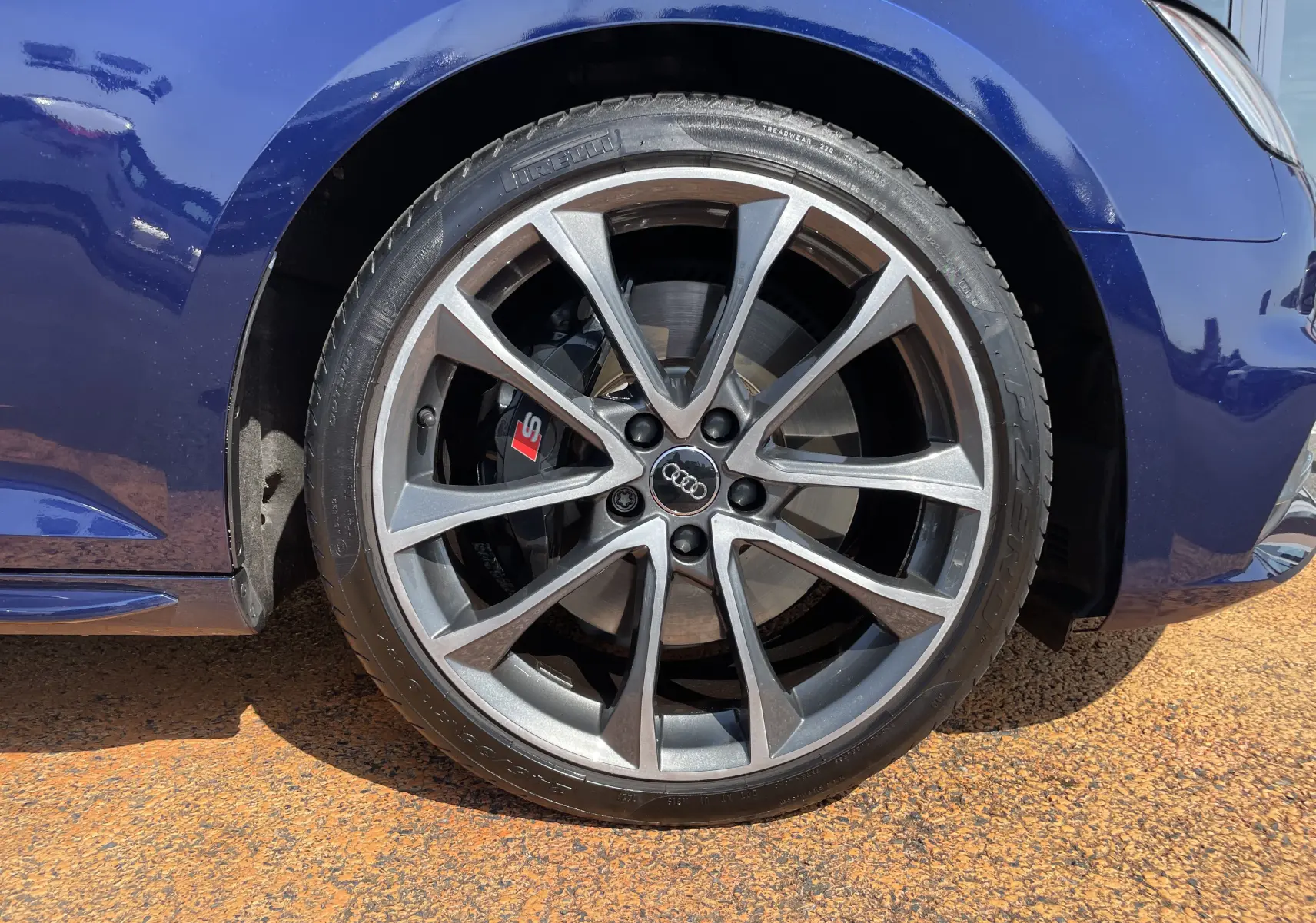 Gros plan sur la roue avant gauche d'une Audi S4 bleu Navarre avec jante alliage et étrier de frein rouge S.