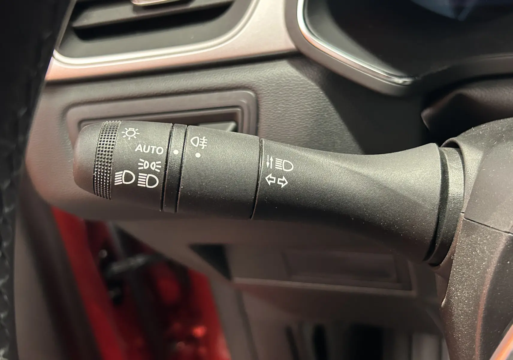 Gros plan sur la commande des feux et clignotants à gauche du volant dans un Renault Captur rouge flamme 2024.
