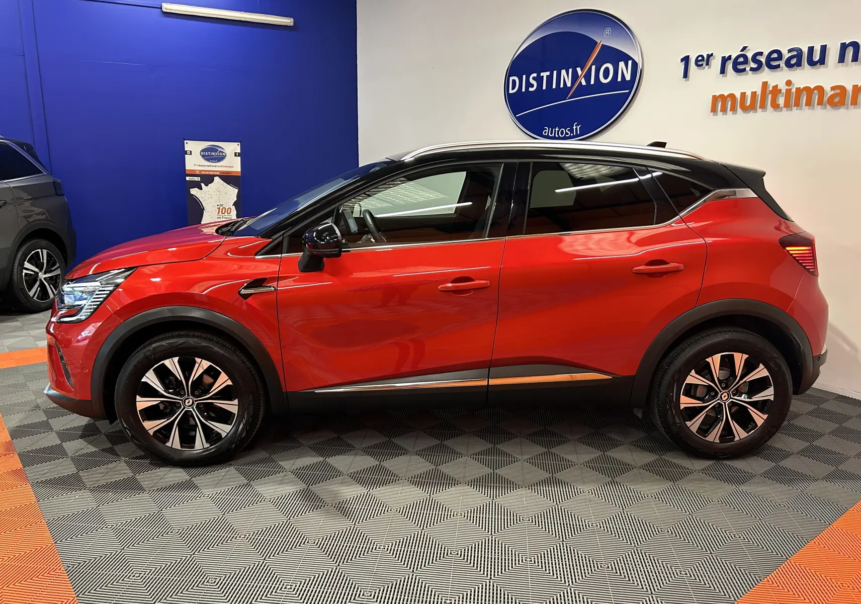 Profil côté gauche d'un Renault Captur 2024 rouge flamme métallisé avec jantes alliage et toit noir en showroom.