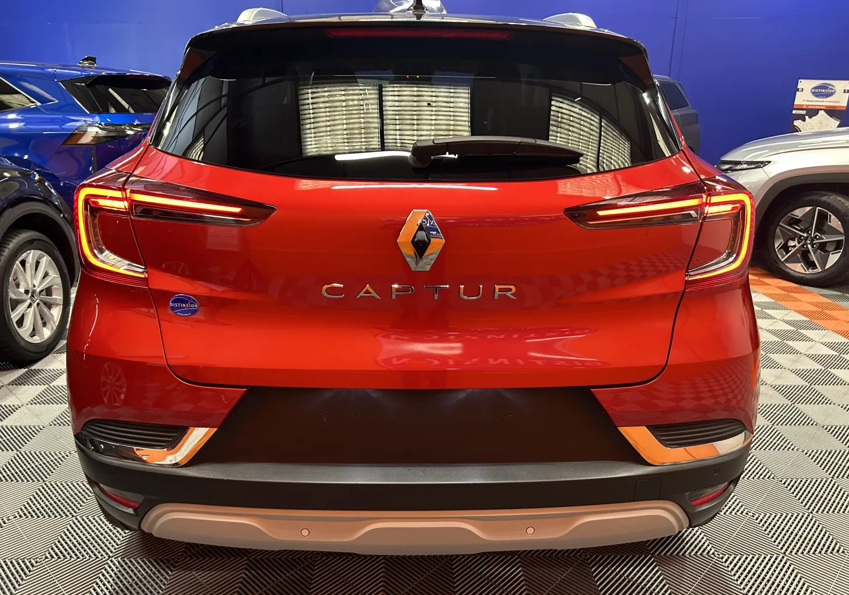 Vue arrière d'un Renault Captur rouge flamme métal 2024 avec feux LED et logo central bien visibles.