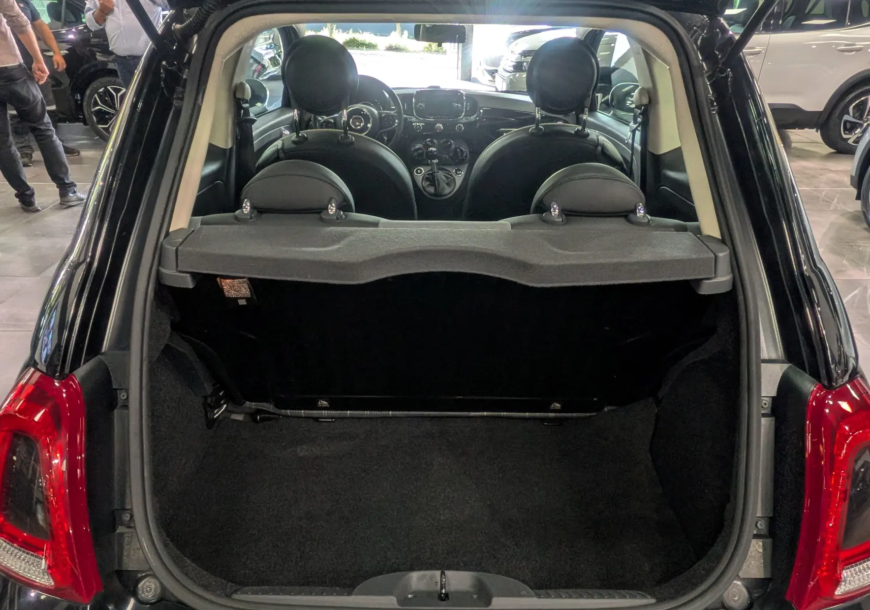 Coffre ouvert vu de l'arrière d'une Fiat 500 noire Crossover Black, intérieur et tableau de bord visibles.