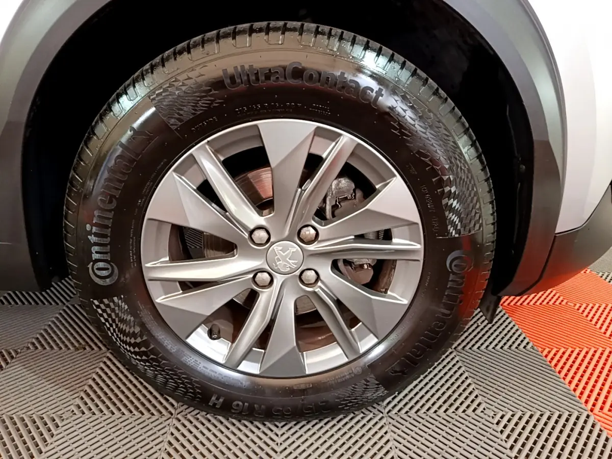 Gros plan sur la roue avant droite d’un Peugeot 2008 gris clair, avec jante alliage et pneu Continental.