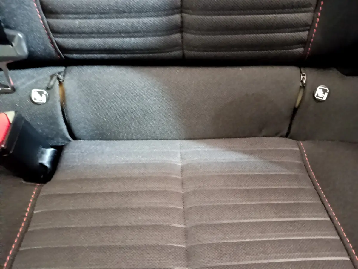 Gros plan sur la banquette arrière noire avec surpiqûres rouges et fixations Isofix du Peugeot 2008 gris clair.
