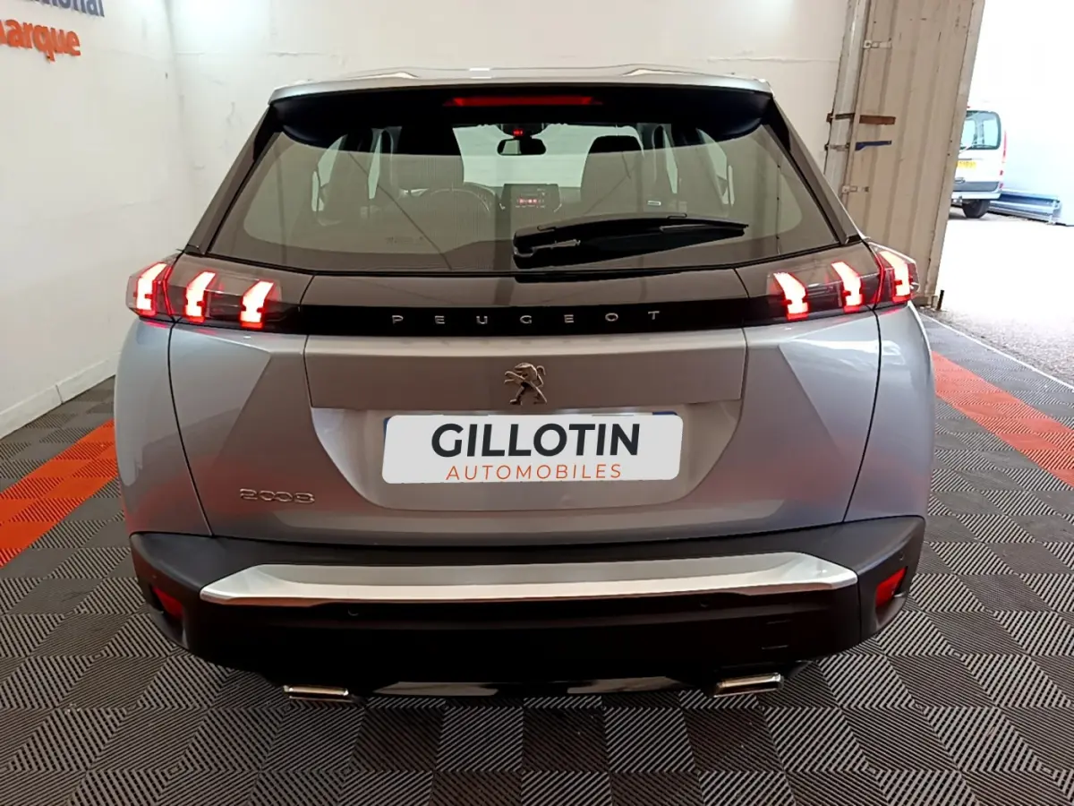 Vue arrière d'une Peugeot 2008 gris clair de 2020 avec feux LED allumés et logo lion visible.