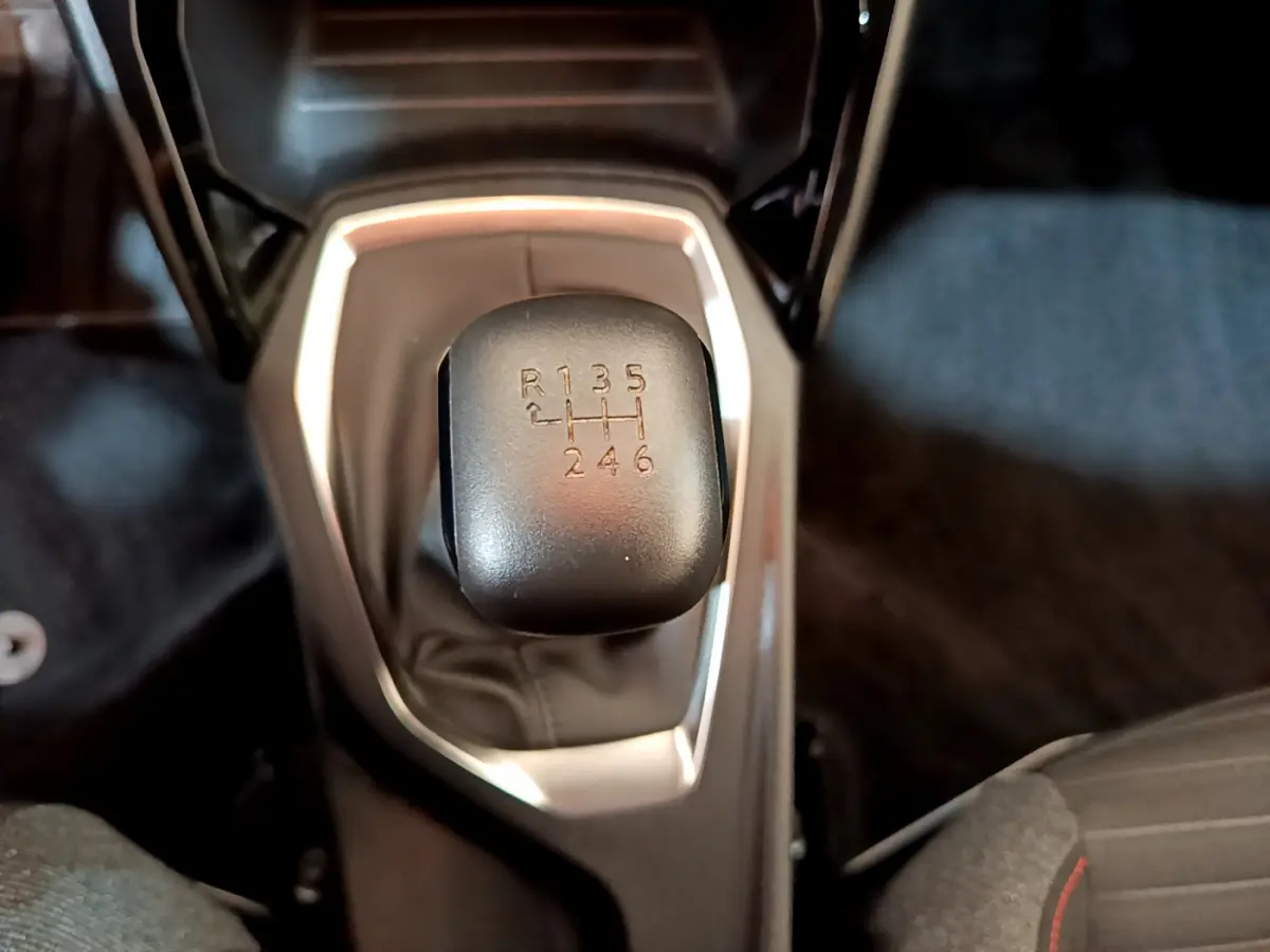 Le levier de vitesses manuel noir de la Peugeot 2008 essence 2020 vu de dessus avec console grise autour.