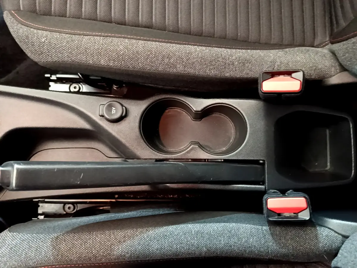 Vue plongeante sur la console centrale du Peugeot 2008 gris clair, avec frein à main et prises 12V visibles.