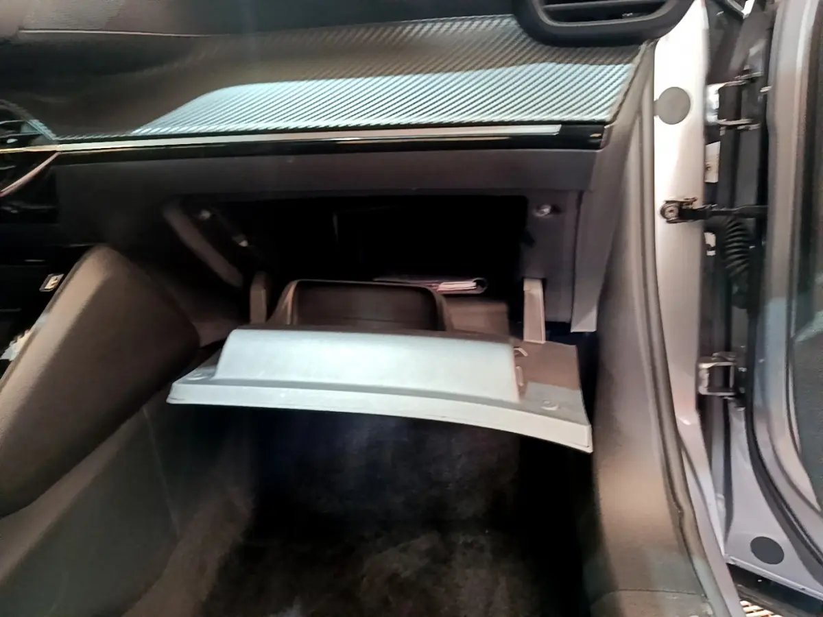 Vue intérieure côté passager du Peugeot 2008 gris clair 2020, boîte à gants ouverte sous tableau de bord noir.