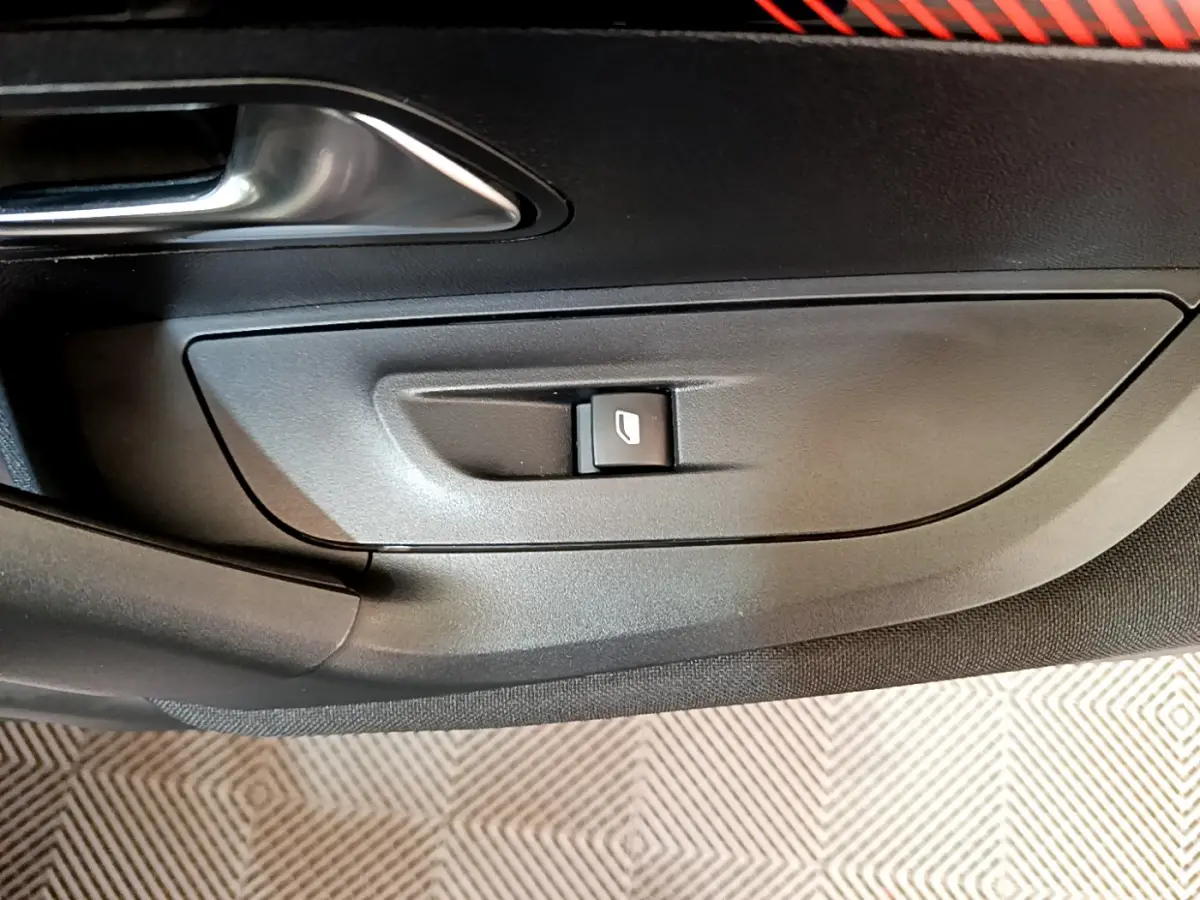 Bouton de commande de vitre électrique sur la porte côté gauche d'un Peugeot 2008 gris clair, intérieur noir.