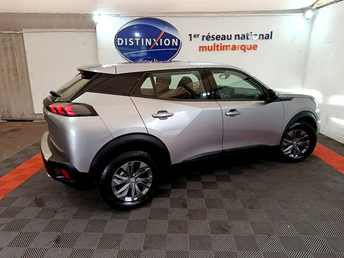 Peugeot 2008 gris clair vue de profil côté droit en intérieur, avec feux arrière LED et jantes alliage.