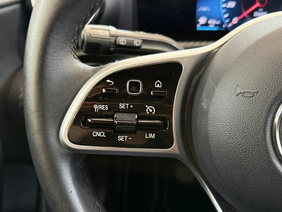 Gros plan sur les commandes de régulateur de vitesse au volant cuir noir de la Mercedes Classe A 180 d Business Line.