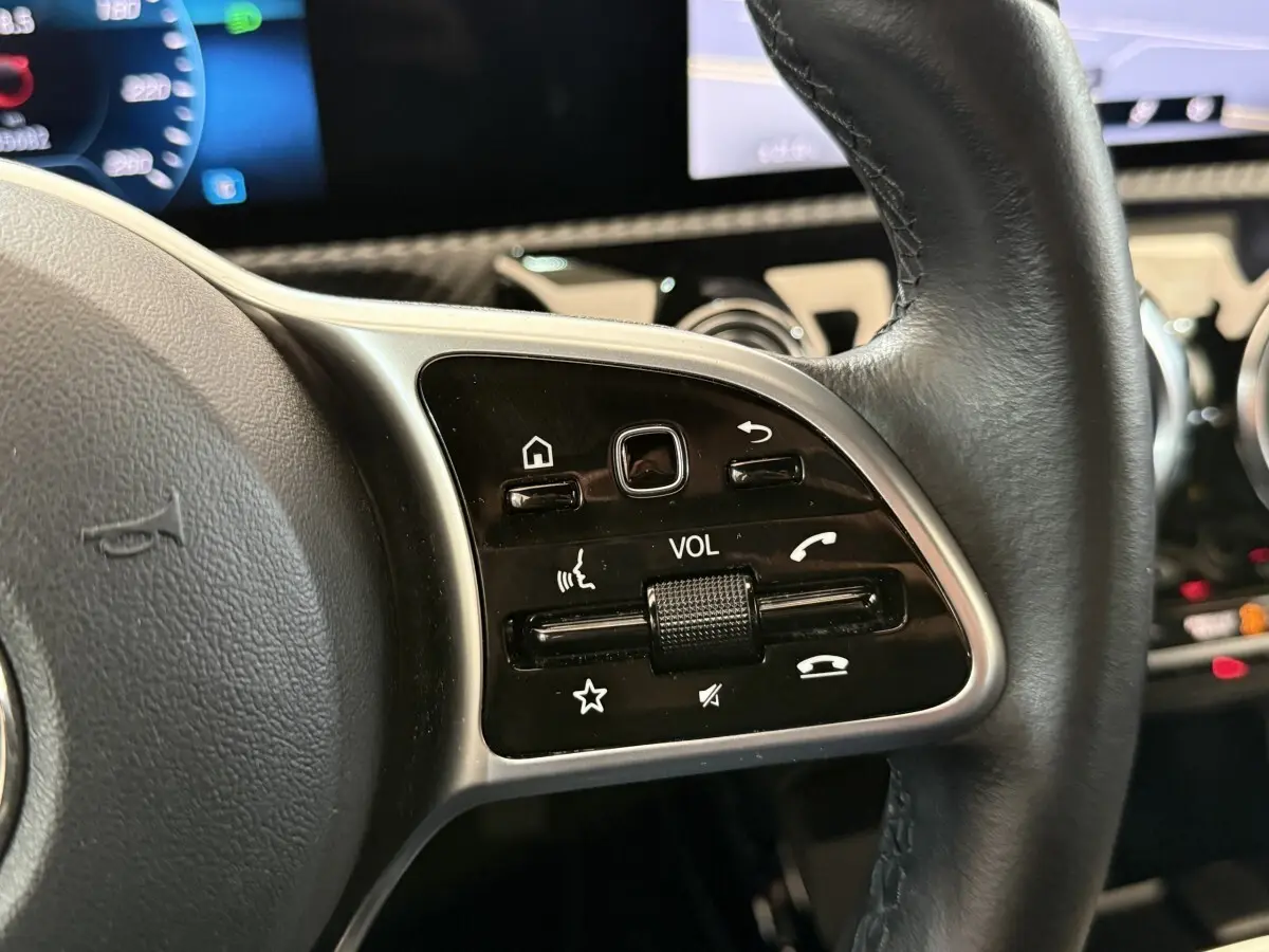 Gros plan sur les commandes du volant cuir côté gauche de la Mercedes Classe A 180 d Business Line 2021.