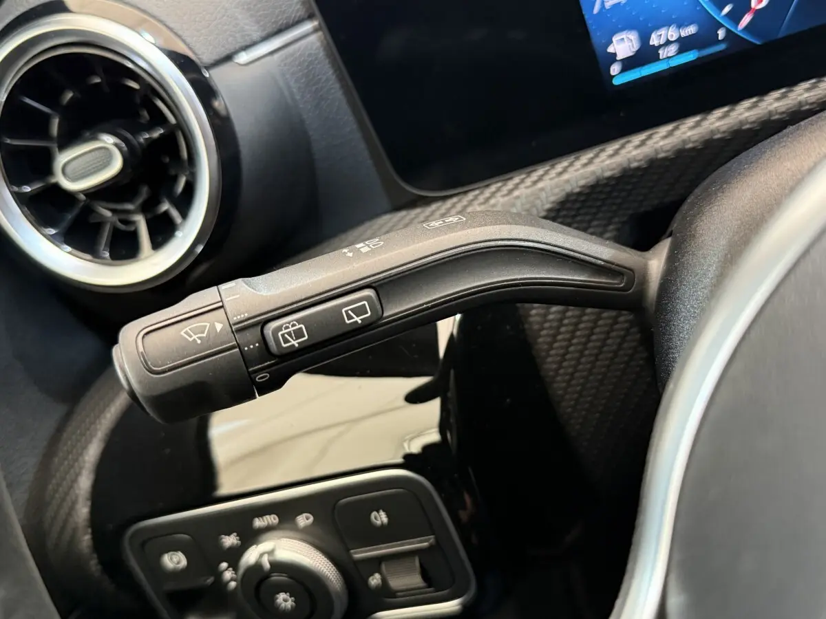 Gros plan sur la commande d’essuie-glaces à gauche du volant dans l’habitacle noir de la Mercedes Classe A 180 d Business Line.