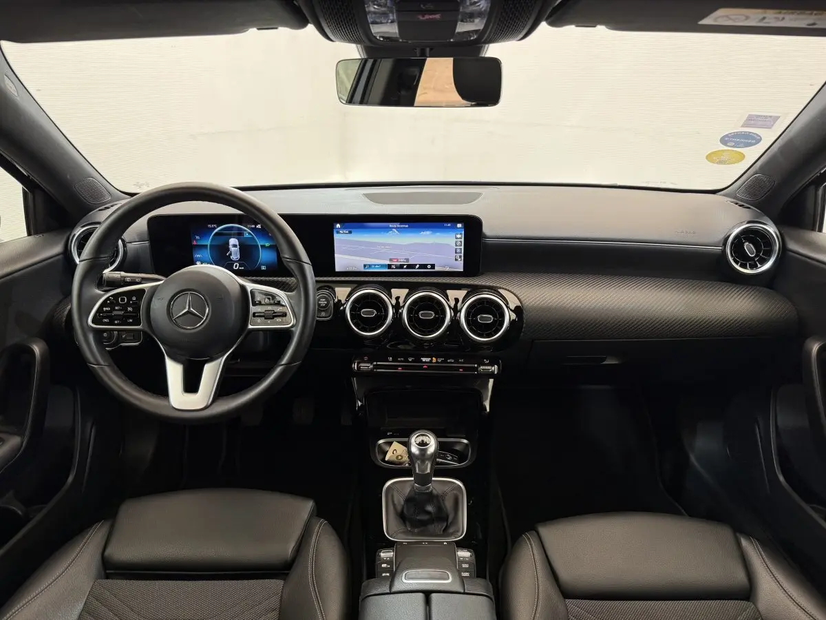 Vue intérieure avant de la Mercedes Classe A 180 d Business Line 2021, tableau de bord noir avec écran tactile et volant cuir.