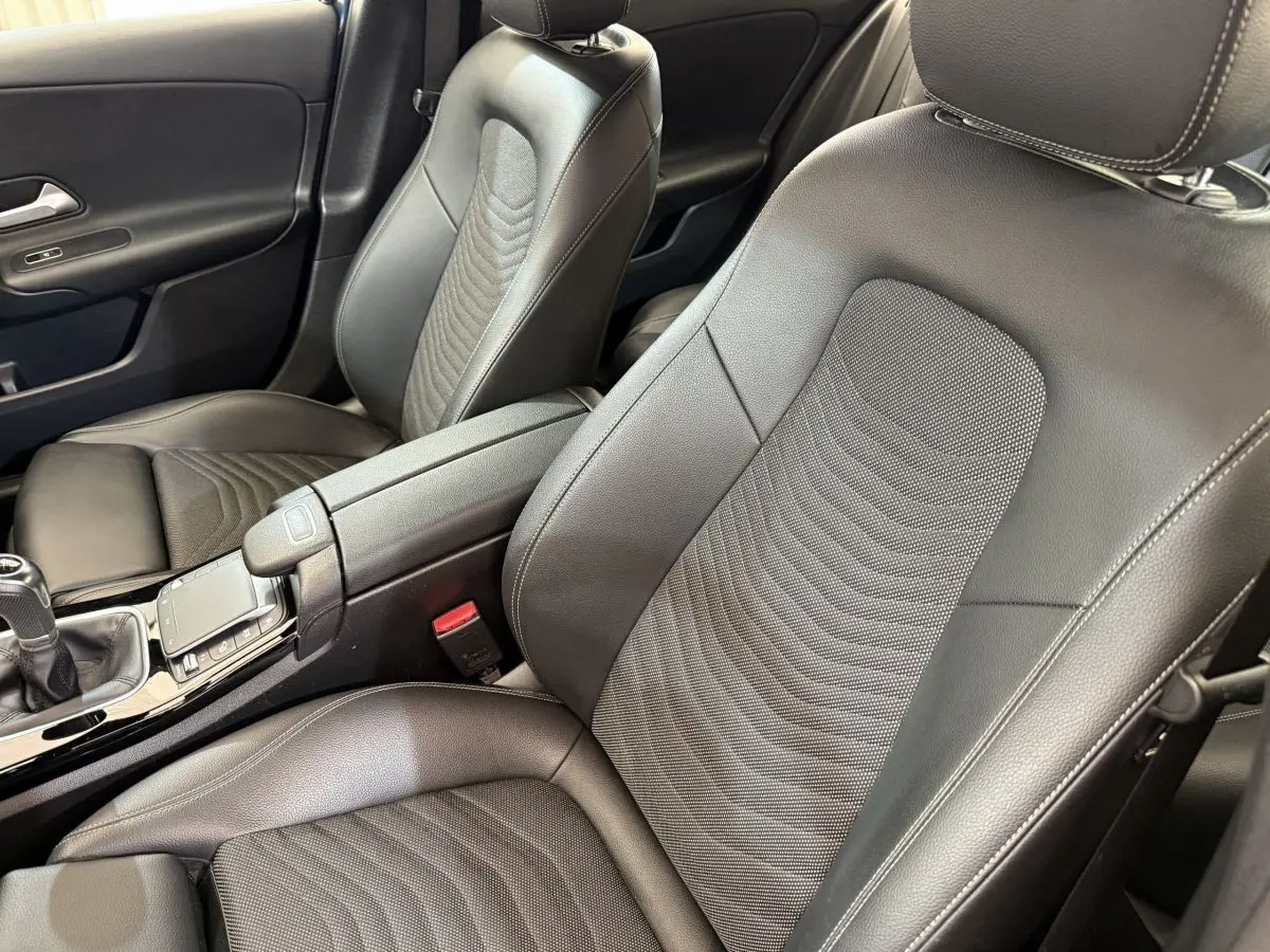 Vue rapprochée des sièges avant en cuir noir et console centrale d'une Mercedes Classe A 180 d Business Line 2021.
