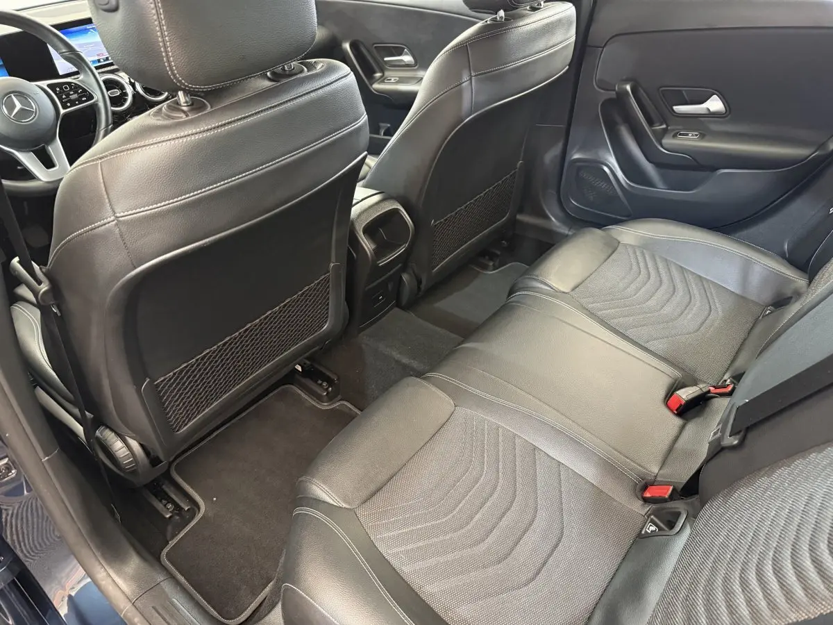 Vue intérieure côté droit sur la banquette arrière noire et les sièges avant en cuir d'une Mercedes Classe A bleu.
