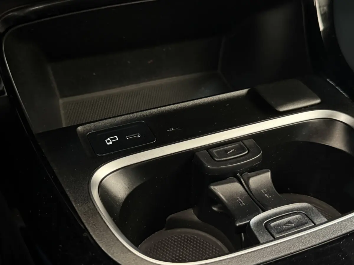 Gros plan sur la console centrale noire de la Mercedes Classe A 180 d Business Line avec prises USB et porte-gobelets.
