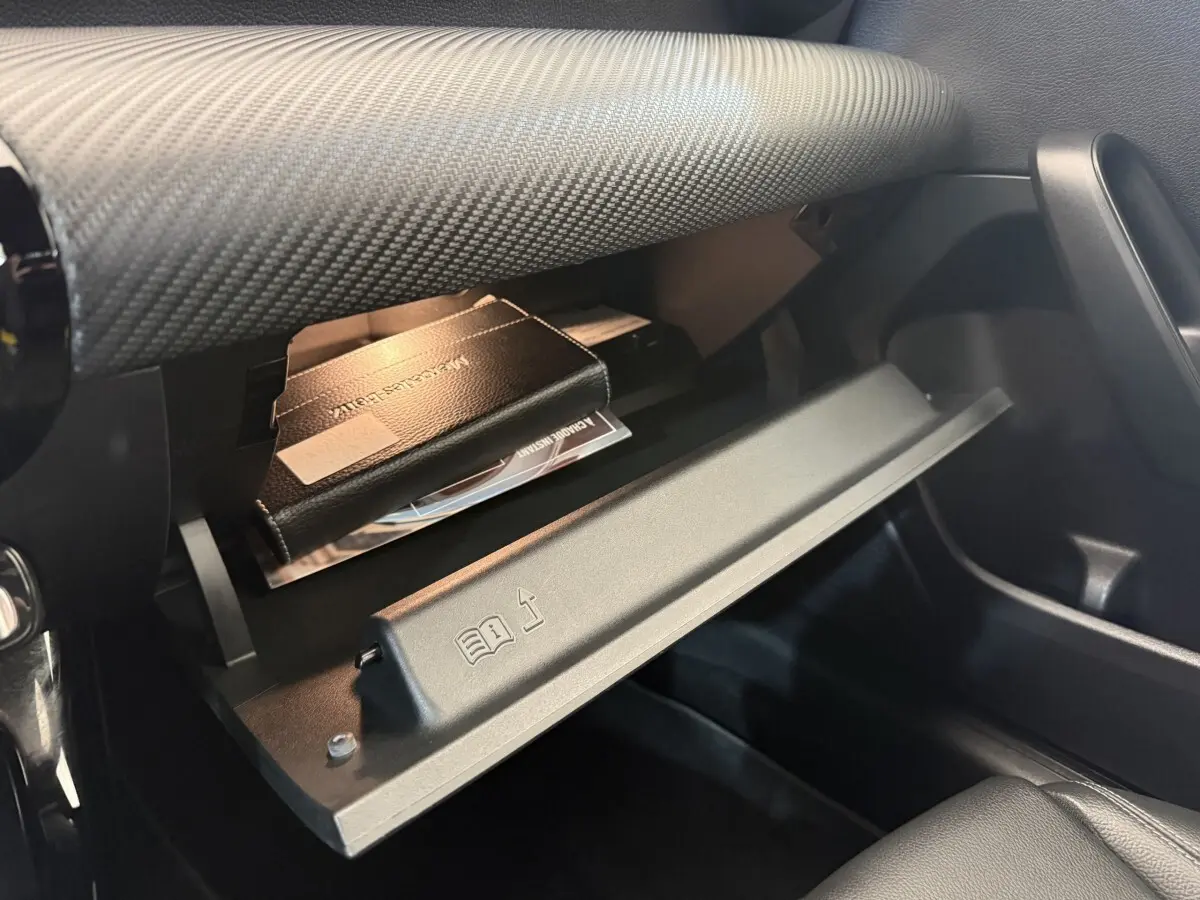 Gros plan sur la boîte à gants ouverte côté passager de la Mercedes Classe A 180 d Business Line, intérieur noir.