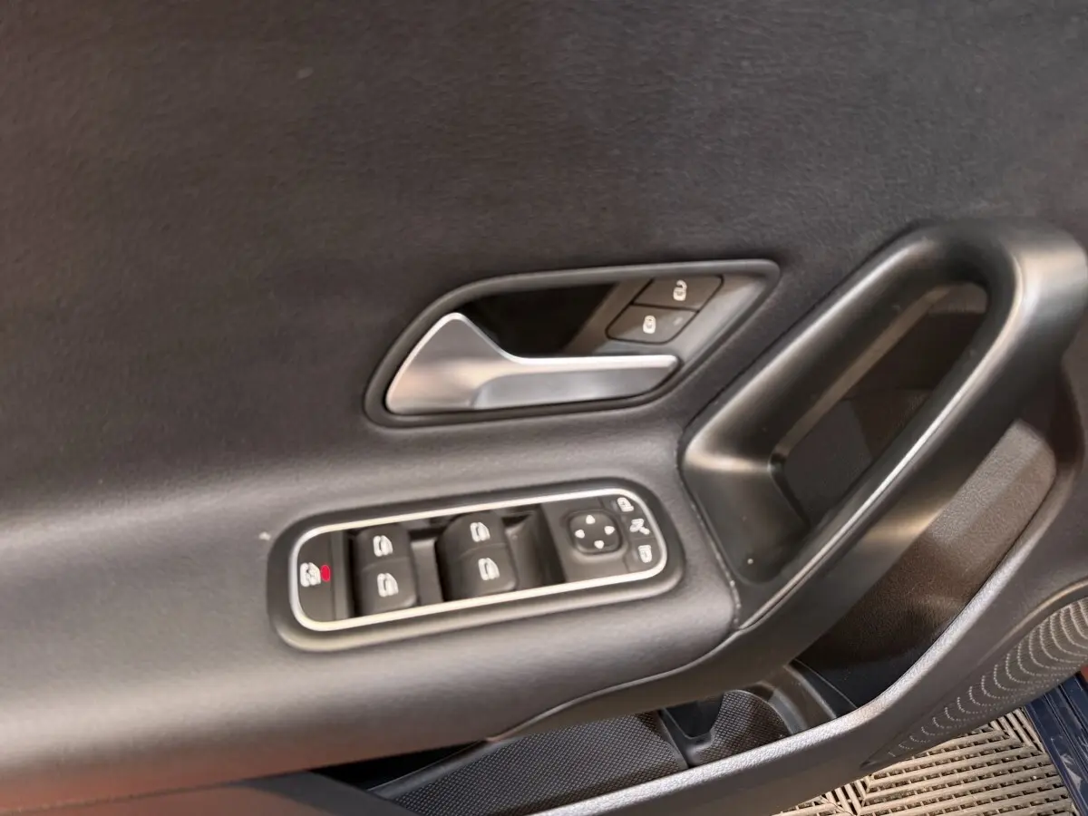 Gros plan sur la porte côté conducteur de la Mercedes Classe A 180 d Business Line bleu, montrant les commandes des vitres et serrures.