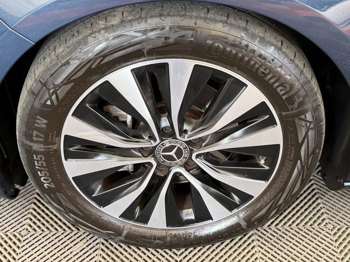 Gros plan sur la roue avant droite d’une Mercedes Classe A bleu, avec jante alliage bicolore et logo central Mercedes.