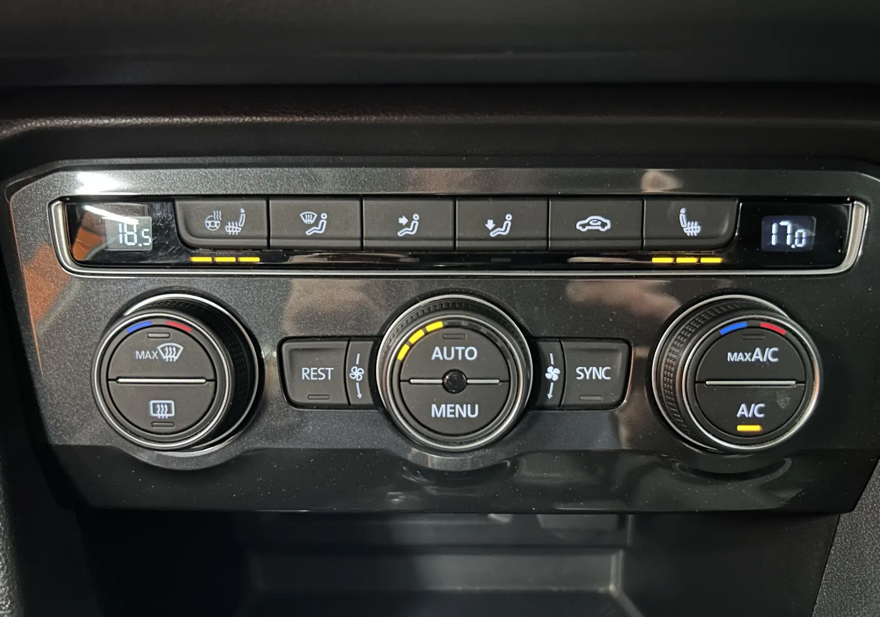 Panneau de commande de climatisation noir du Volkswagen Tiguan Allspace blanc, avec affichage digital et boutons rétroéclairés.