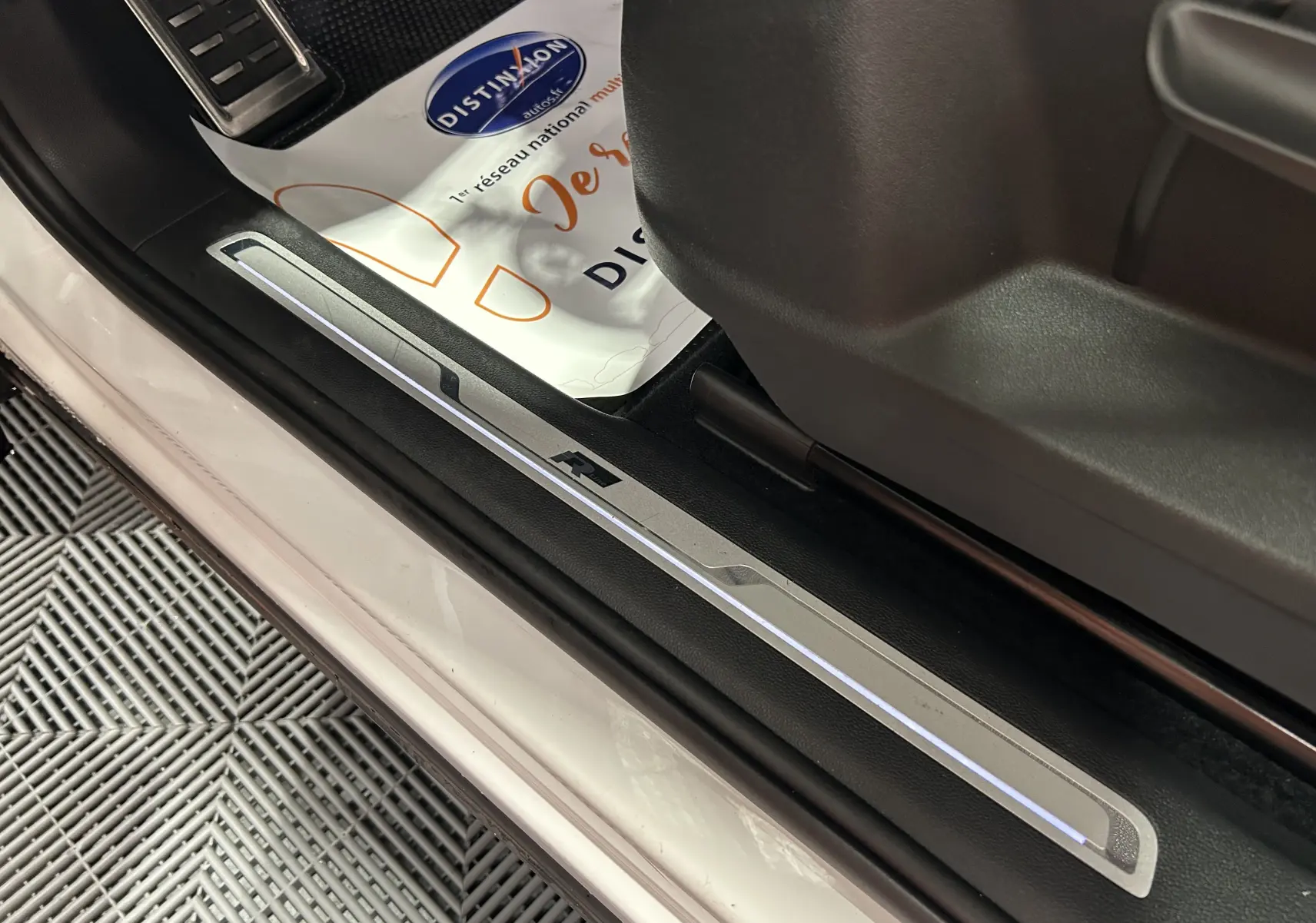 Gros plan sur la plaque de seuil de porte avant droite blanche du Volkswagen Tiguan Allspace avec logo R rétroéclairé.