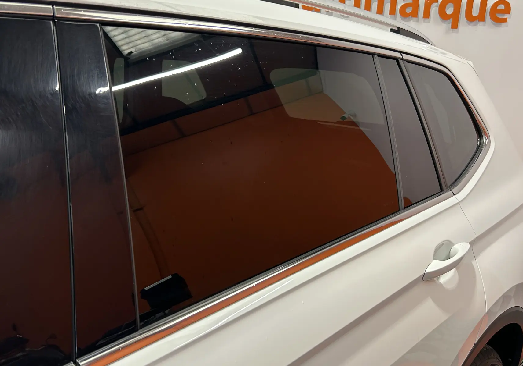 Vue latérale droite du Volkswagen Tiguan Allspace blanc avec vitres teintées et poignée de porte visible.