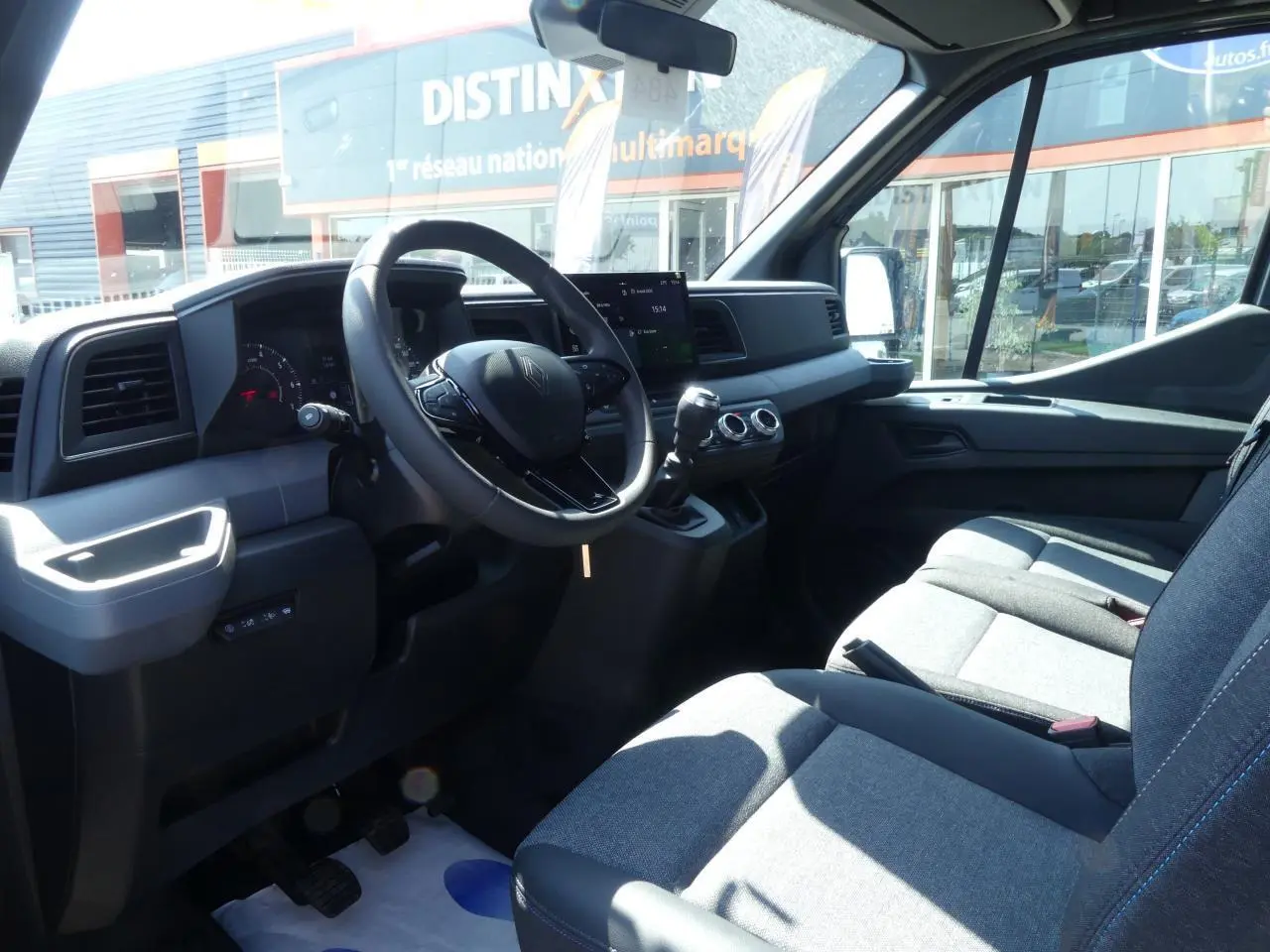 Intérieur du Renault Master Extra 2025 vu côté conducteur, volant multifonction et sièges tissu gris chiné visibles.