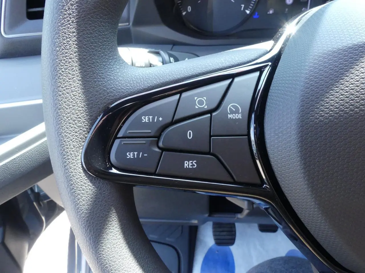 Gros plan sur les commandes du volant noir du Renault Master Extra gris, côté gauche du poste de conduite.