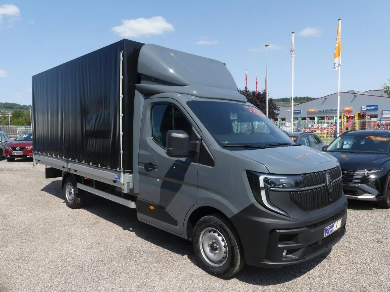 Renault Master Extra gris vu en 3/4 avant droit avec bâche noire et calandre verticale distinctive.