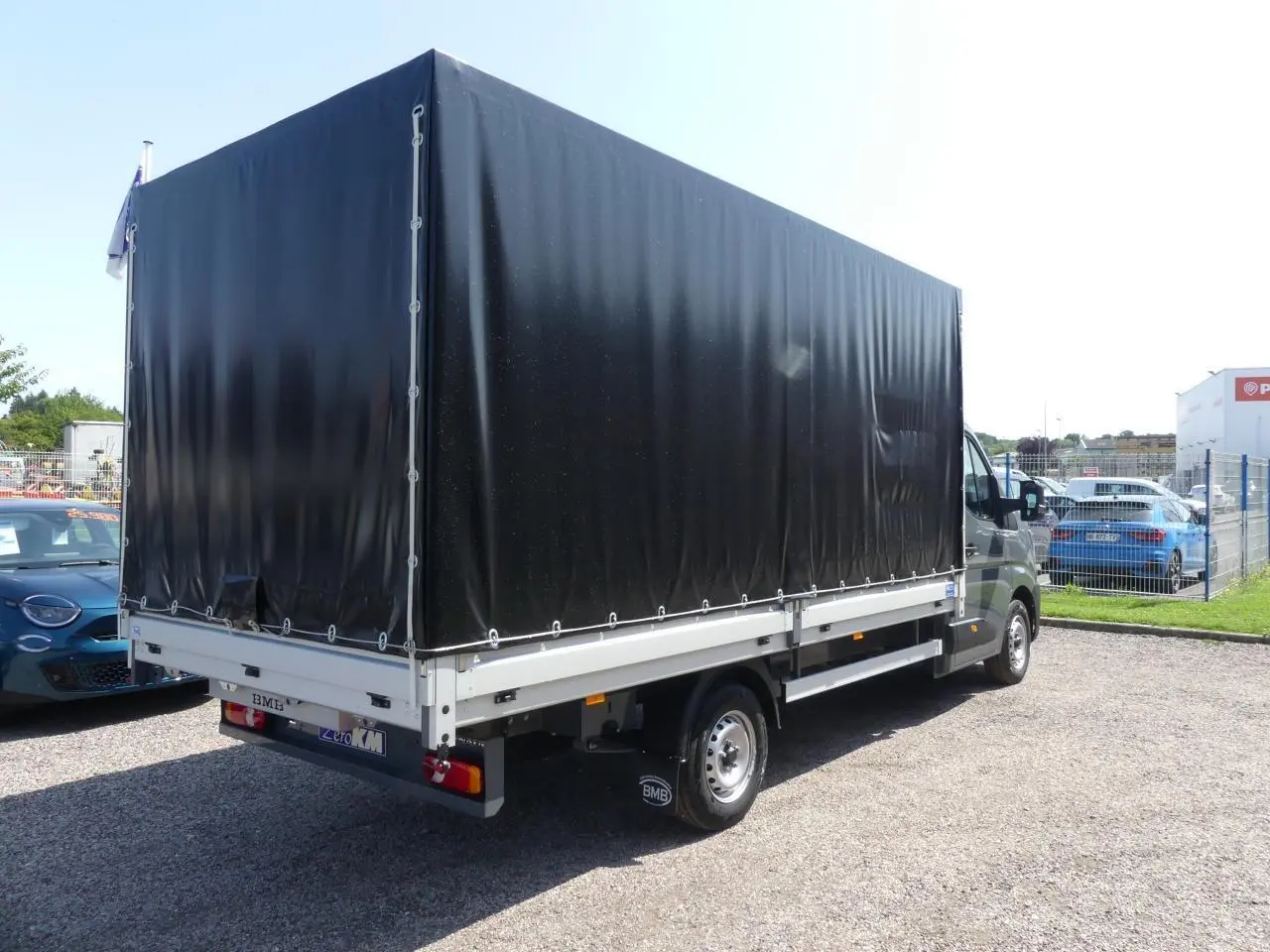 Renault Master Extra 2025 gris, vue 3/4 arrière droit avec bâche noire couvrant la zone de chargement.