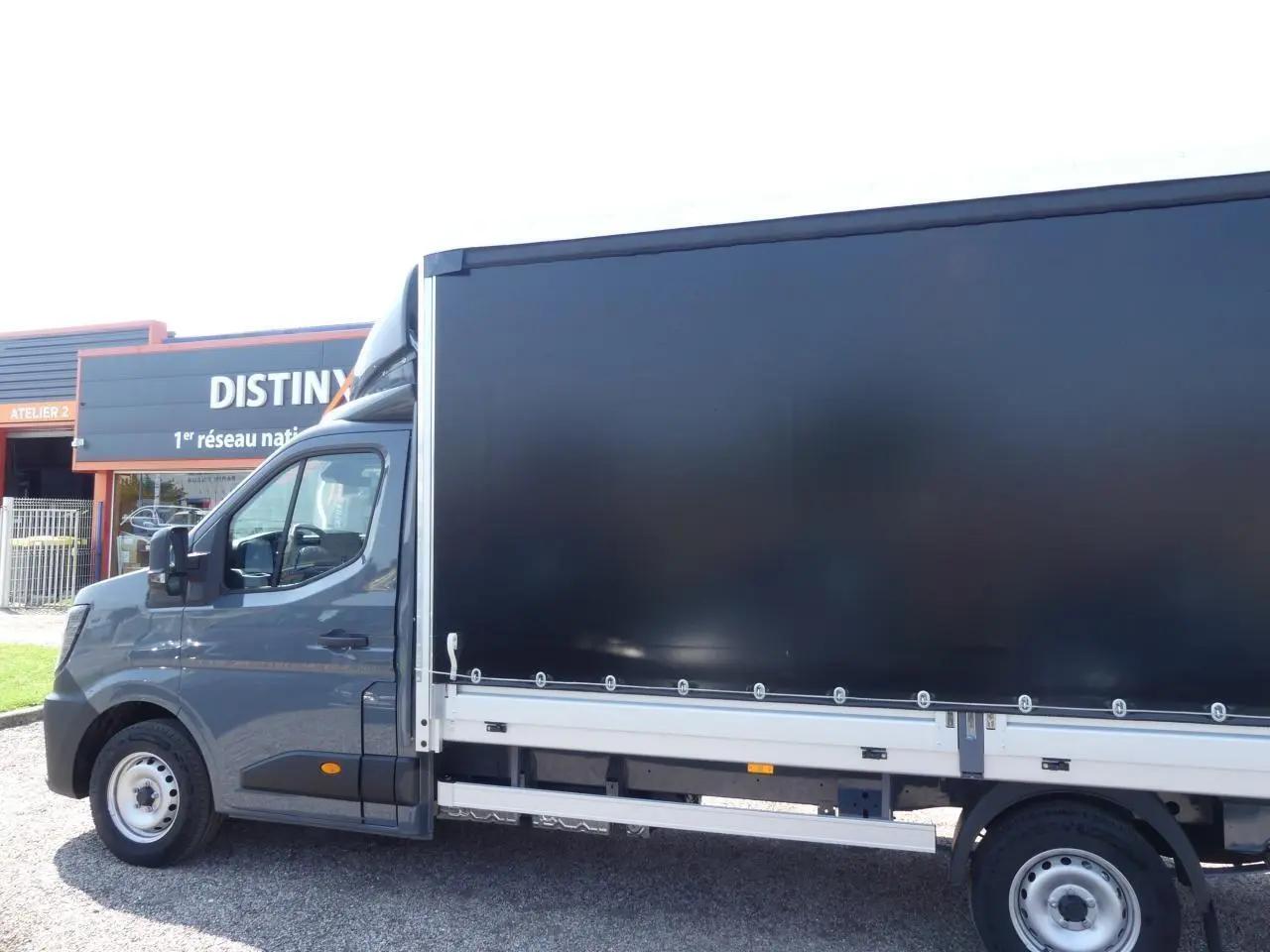 Vue de profil côté gauche d'un Renault Master Extra gris avec bâche noire et jantes tôles 16 pouces.