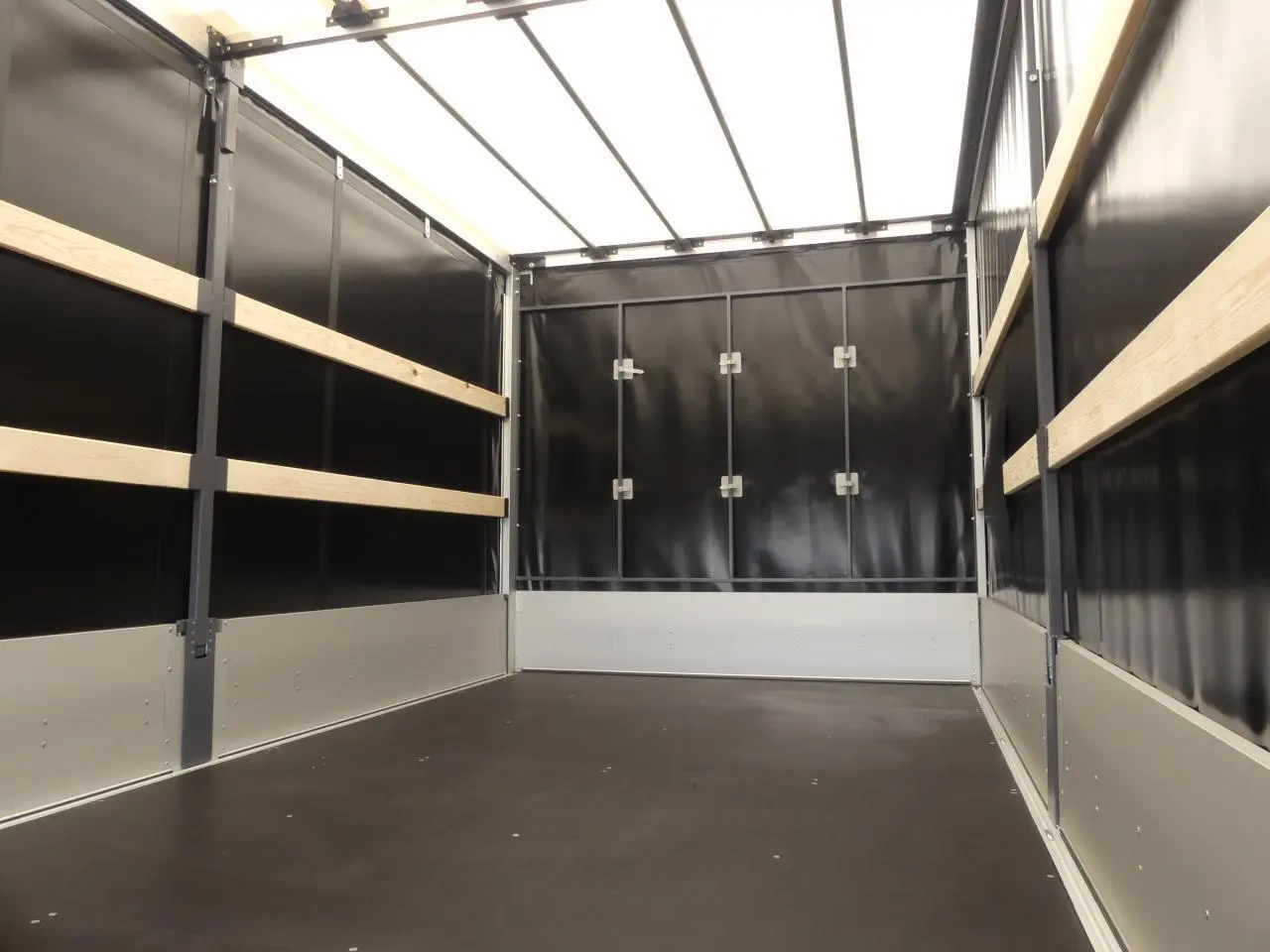 Intérieur de la bâche noire du Renault Master Extra 2025, montrant les parois latérales et arrière avec renforts bois.