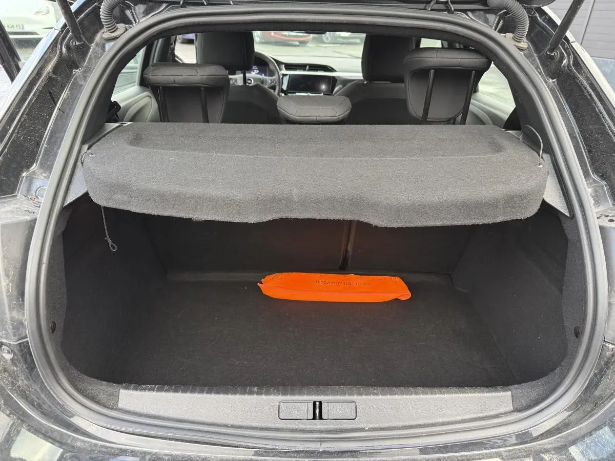 Coffre ouvert d'une Opel Corsa noire vue de l'arrière avec cache-bagages et triangle de sécurité orange.