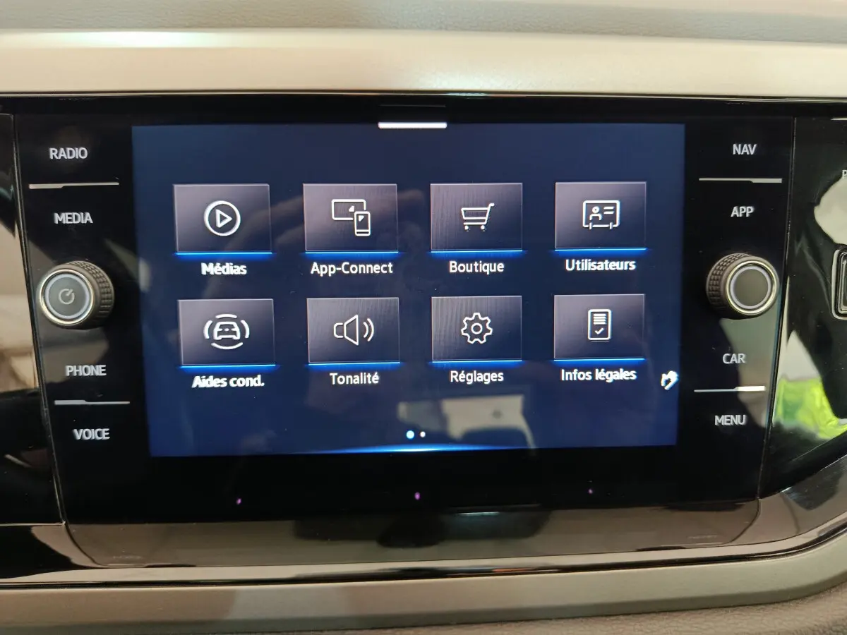 Écran tactile central du tableau de bord de la Volkswagen Polo blanche, affichant le menu multimédia et réglages.