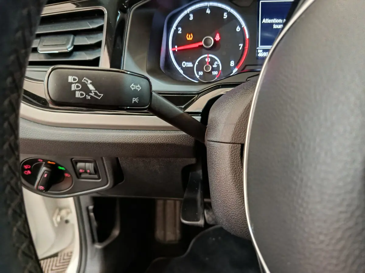 Gros plan sur le tableau de bord et la commande des phares d'une Volkswagen Polo blanche, version 2020, côté conducteur.