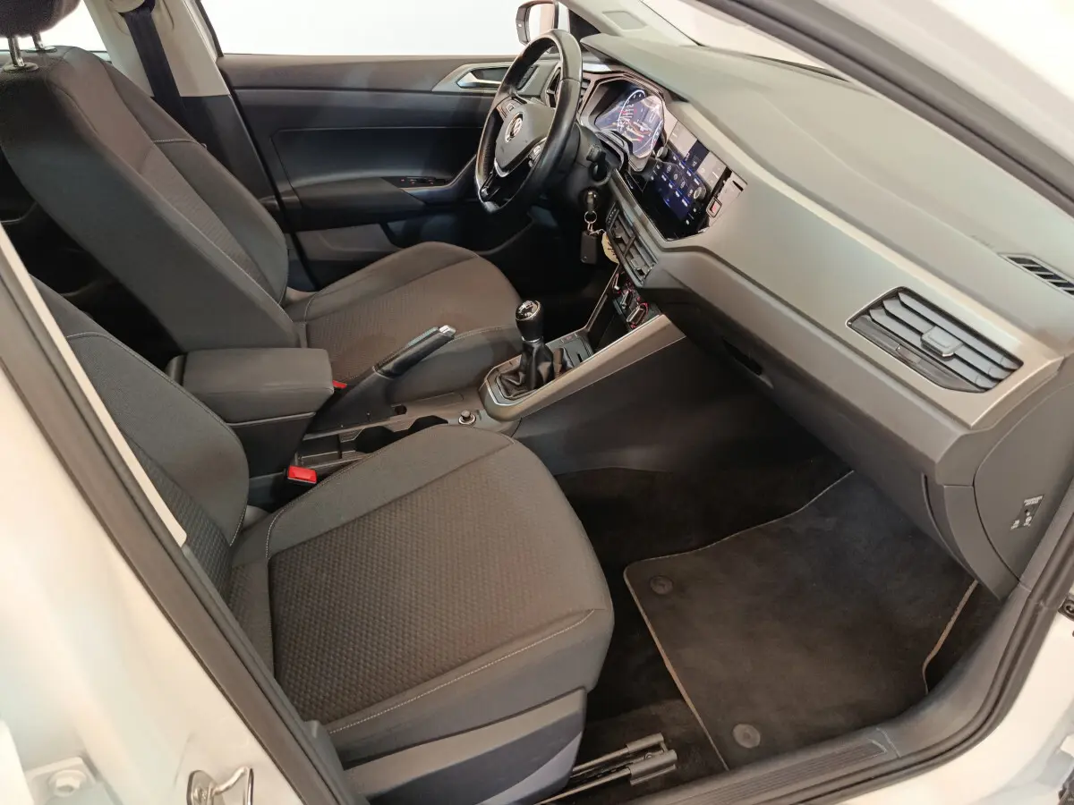 Intérieur avant droit de la Volkswagen Polo blanche 2020, sièges noirs, volant cuir, tableau de bord digital et boîte manuelle.