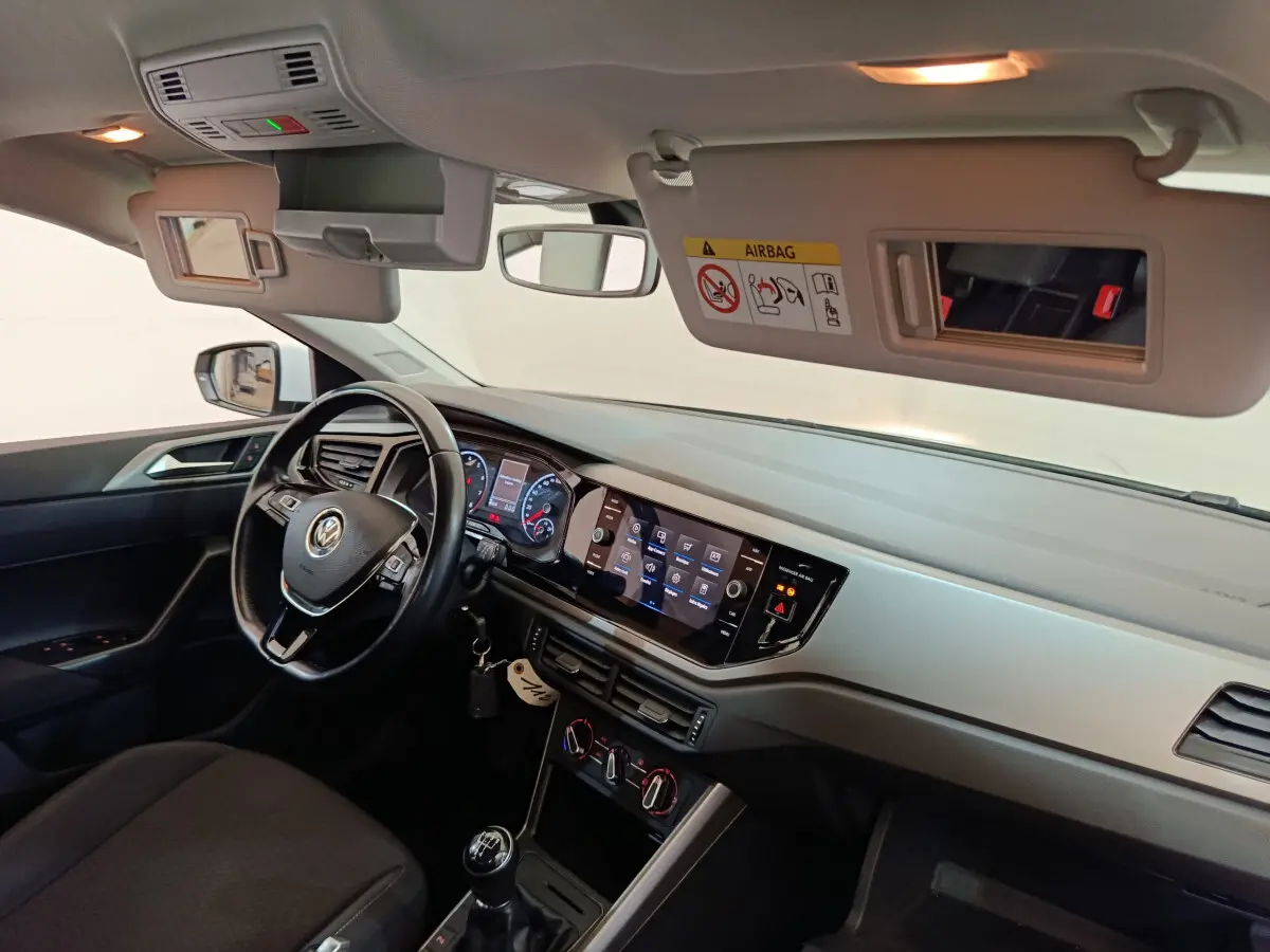 Intérieur avant droit d'une Volkswagen Polo blanche 2020, tableau de bord avec écran tactile et volant cuir multifonctions.